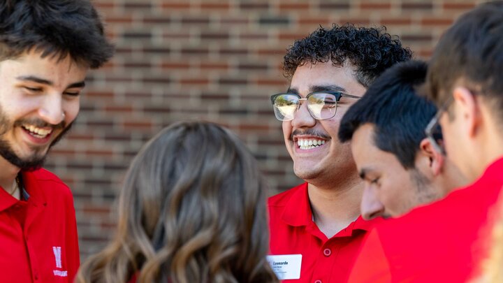 Leonardo Luna-Duran stands with a group of people in red shirts standing together outdoors near a brick wall.