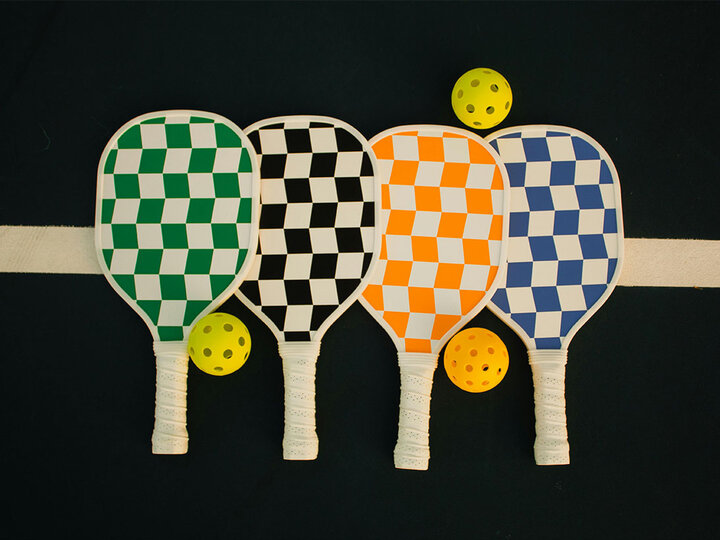 Four pickleball rackets and three balls.