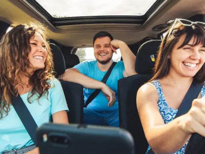 three people sit inside a vehicle.