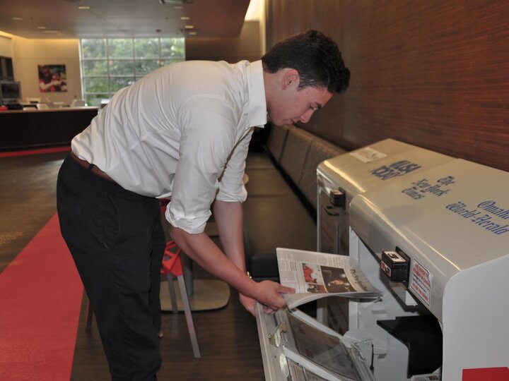 A student stocks a vending machine with newspapers